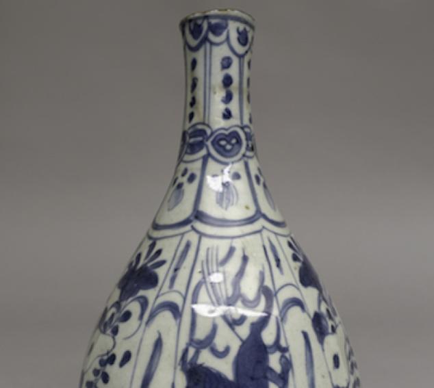 A white vase with a long skinny neck and blue decorative details.