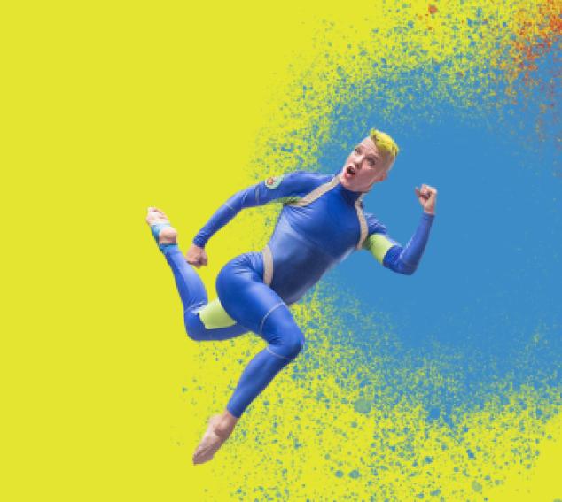 Dancer in blue suit jumping against bright background with paint splatters