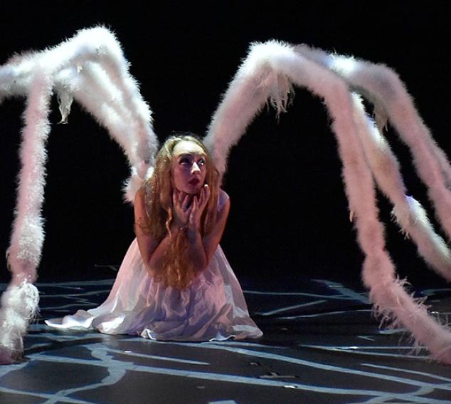 A dancer in a spider-like costume against a dark background