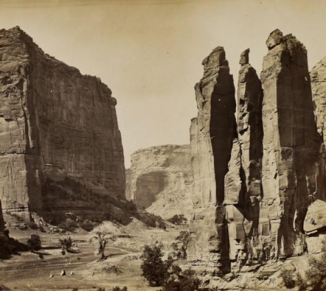 A sepia toned photograph with rock formations in the foreground and background.