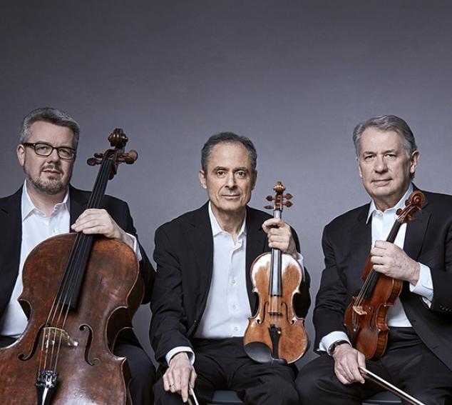 Three musicians in suits holding string instruments against a gray background