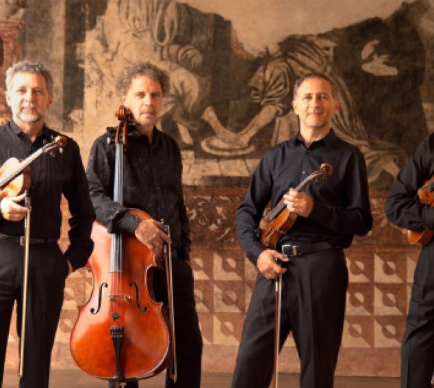Four performers stand with their string instruments in a hallway