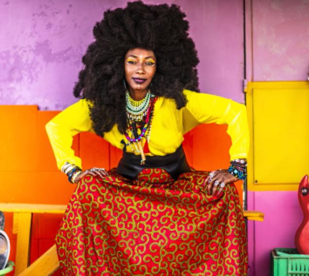 a female performer with a guitar against a colorful background