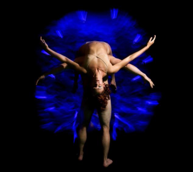 Two performers intertwined against a dark background
