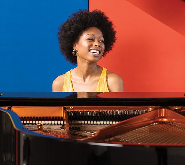 Isata Kanneh-Mason sitting at a grand piano against a colorful background
