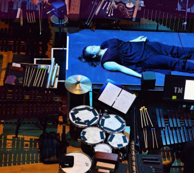 bird's eye view of a percussion pit. An artists lays on a blue table in focus